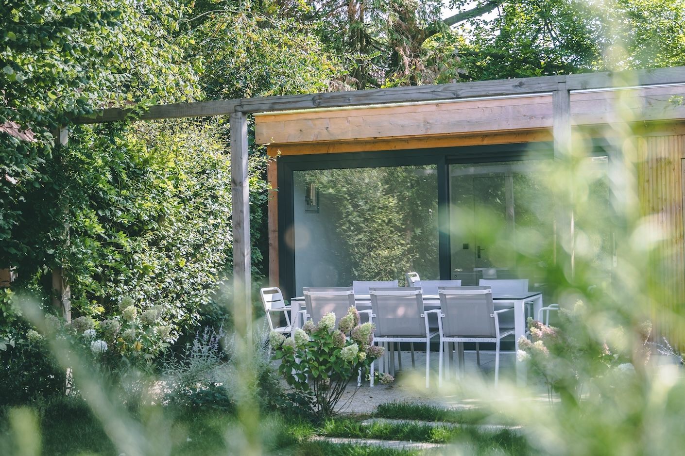 Tuinrenovatie door de hoveniers van Snijers Tuinen. Een volgroeide groene tuin met uniek terrasoverkapping. 