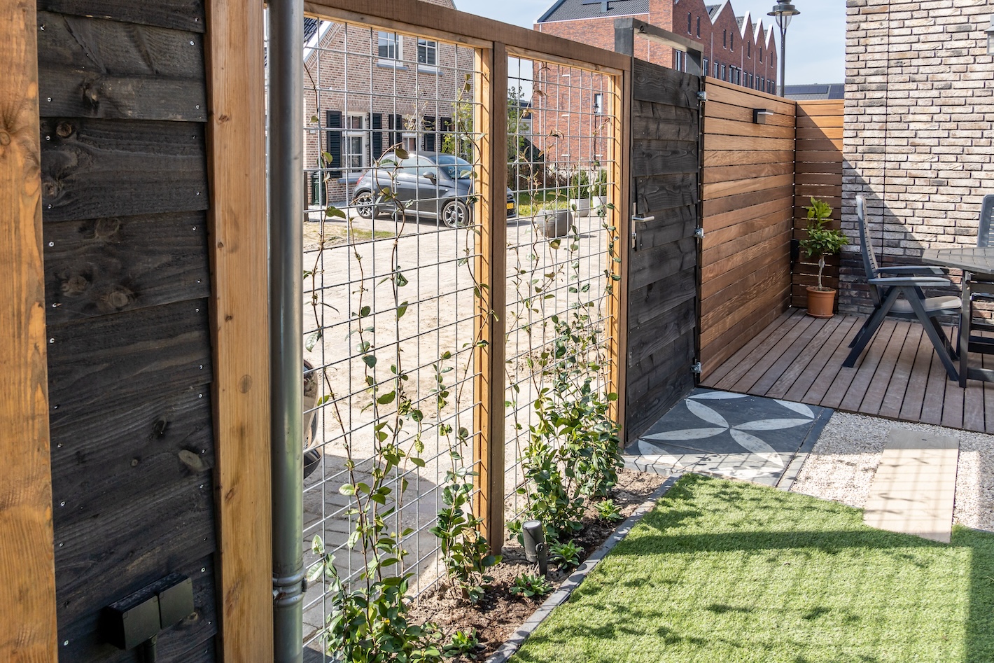 Houten schutting met metalen rooster en klimplanten bij tuinaanlegproject in Almere door Snijers Tuinen.